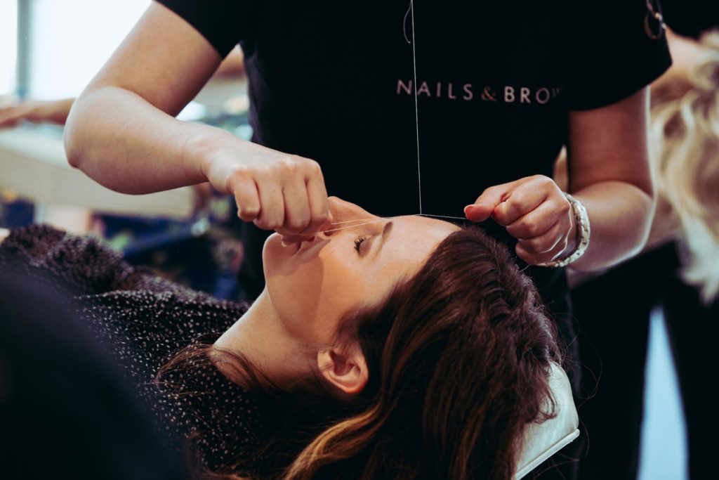 A technician doing a woman's eyebrow treatment